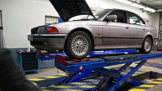 Ein silberner 5er BMW ist in einer Werkstatt auf der Hebebühne © NDR 
