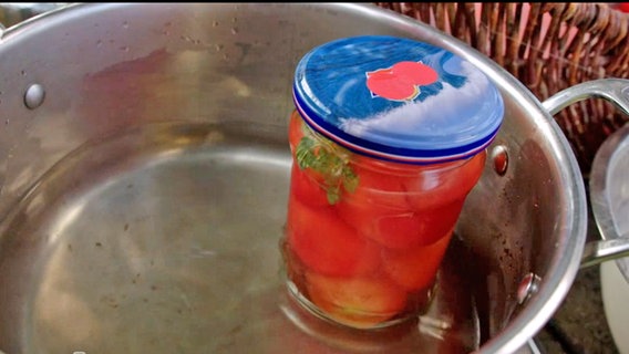 Ein Einweckglas mit Tomaten steht in einem Kochtopf mit Wasser. © NDR Foto: Udo Tanske