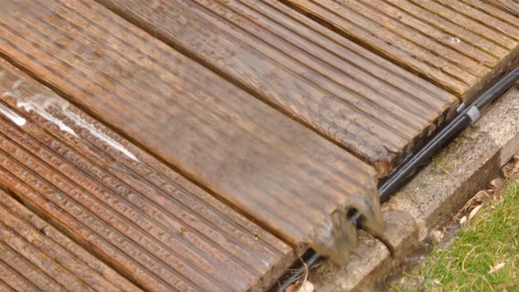 Wasser läuft von gereinigten Holzdielen. © NDR 