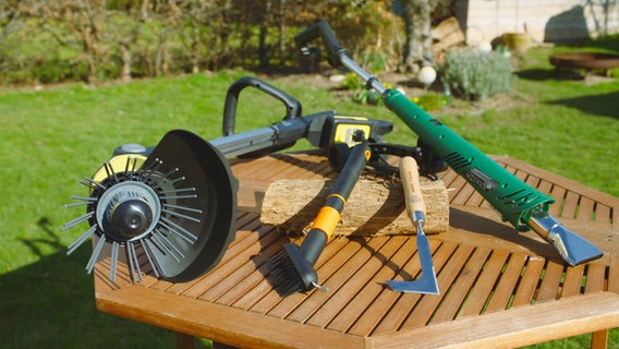 Auf einem Gartentisch liegen vier verschiedene Produkte zur Unkrautentfernung im Garten. © WDR 
