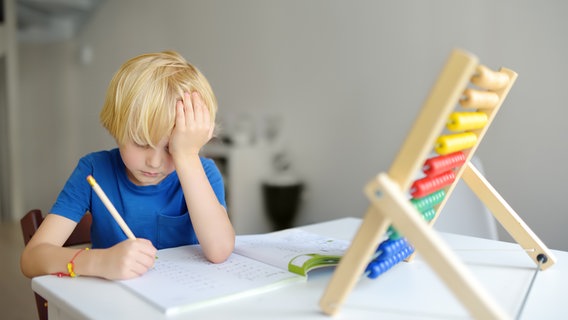 ADHS bei Kindern: Ein Kind sitzt unglücklich über den Hausaufgaben © colourbox.de 