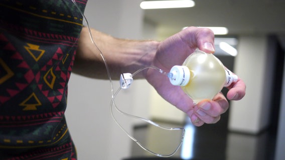 Eine Hand hält einen kleinen Plastikball mit Antibiotikum. © NDR Foto: Christian Baars
