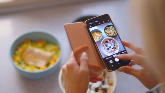 Frau macht Fotos von drei Schüsseln mit Essen, die vor ihr stehen. © NDR 