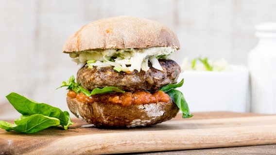 Ein Rindfleisch-Grünkern-Burger auf einem Brett. © NDR Foto: Claudia Timmann