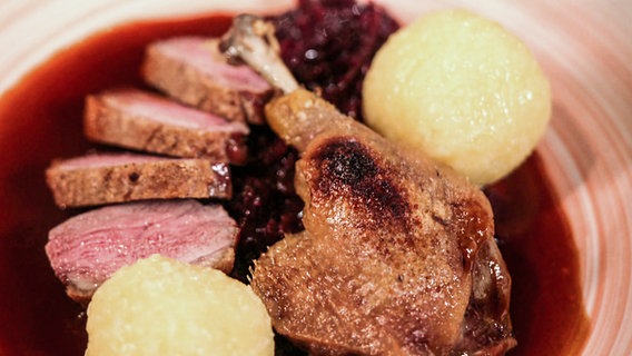 Entenbrust und Entenkeule mit Rotkohl und Kartoffelklößen auf einem Teller angerichtet. © NDR 