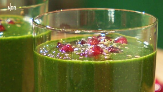 Grüner Smoothie garniert mit Granatapfelkernen.  