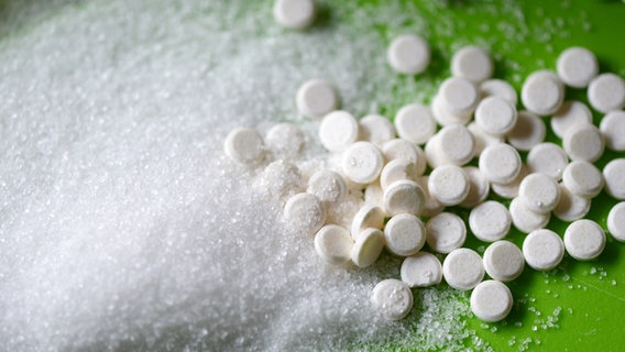 Süßstoff in Tabletten- und Pulverform liegt auf einer grünen Unterlage. © picture alliance / Jens Kalaene/dpa-Zentralbild/dpa | Jens Kalaene 