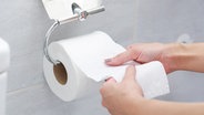 Eine Frau reißt Toilettenpapier von einer Rolle ab. © colourbox Foto: -