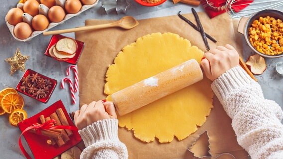 Zwei Hände rollen Teig auf einem Stück Backpapier aus. © Fotolia Foto: Karepa