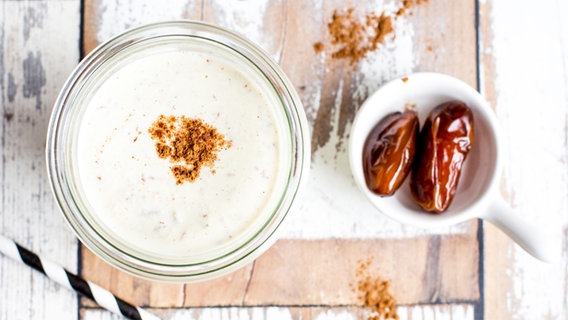 Ein Glas mit Cashewmilch und zwei Datteln in einer Schüssel stehen auf dem Tisch. © NDR Foto: Claudia Timmann