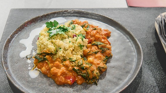 Kichererbsen-Curry mit Granatapfel-Bulgur auf einem Teller angerichtet. © NDR / Fernsehmacher GmbH Foto: Gunnar Nicolaus
