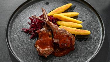 Lammkotelett mit Schupfnudeln und Rotkohl auf einem Teller angerichtet. © NDR / Fernsehmacher GmbH Foto: Markus Hertrich