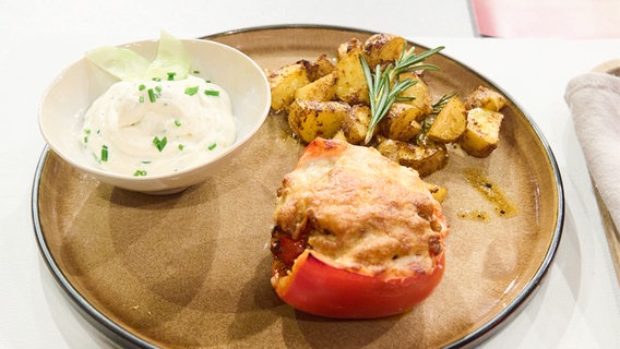 Gefüllte Paprika mit Rosmarin-Kartoffeln und Frühlingsquark auf einem Teller angerichtet. © NDR / Fernsehmacher GmbH Foto: Gunnar Nicolaus