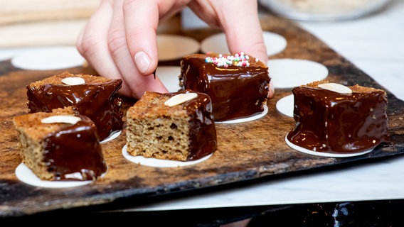 Brauner Kuchen wird mit einem Zuckerguss verziert. © NDR Foto: Claudia Timmann