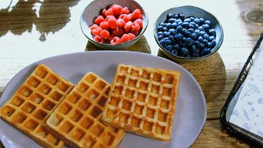 Dinkel-Waffeln auf einem Teller, daneben Himbeeren und Früchte. © Screenshot nonfictionplanet 
