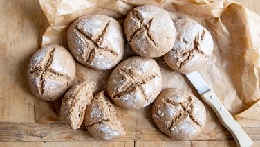 Emmerbrötchen und ein Brotmesser auf einem Holztisch. © NDR Foto: Claudia Timmann
