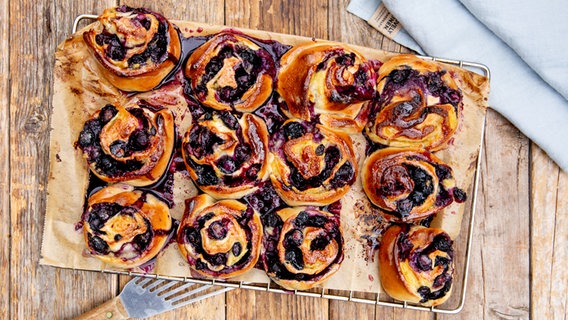 Hefeschnecken mit Blaubeerfüllung auf einem Kuchengitter. © NDR Foto: Claudia Timmann