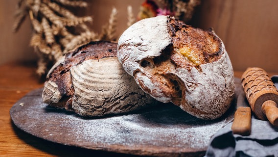 Zwei Sauerteig-Kartoffelbrote liegen auf einem Holzbrett. © NDR Foto: Björn Lindenblatt