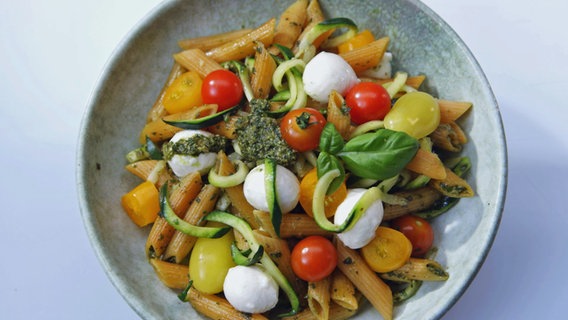 Kichererbsen-Pasta mit Zucchini, Tomaten und Mozzarella auf einem Teller serviert © NDR 