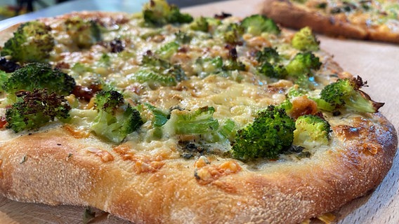 Pizza mit Crème fraîche, Nordseekrabben und Brokkoli auf einer Holzplatte © NDR 