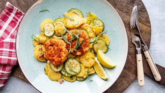 Ein Teller mit Lachsfrikadellen und einem Kartoffelsalat. © NDR Foto: Claudia Timmann