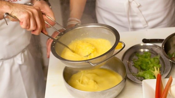 Ali Güngörmüs streicht die fertige Paprika-Rhabarber-Suppe durch ein Sieb. © NDR Foto: Claudia Timmann