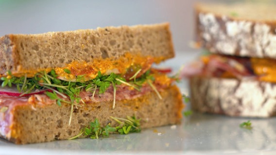 En Sandwich mit Basilikum-Frischkäse-Aufstrich und Salami. © NDR 