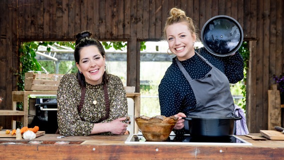 Köchin Zora Klipp und Fleischhändlerin Lina Kypke stehen am Tresen einer Outdoorküche. © NDR Foto: Claudia Timmann