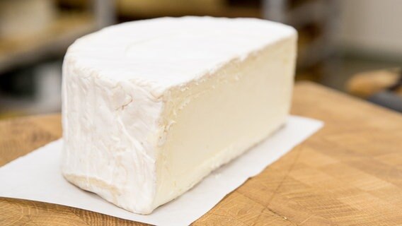 Ein Stück Käse der Sorte Delice de Bourgogne auf einem Holzbrett © NDR Foto: Claudia Timmann