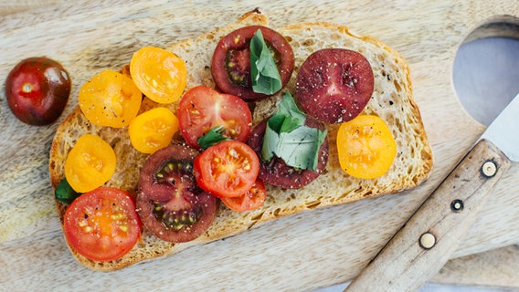 Eine Scheibe geröstetes Brot, belegt mit bunten Tomaten. © NDR Foto: Claudia Timmann