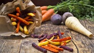Alte Gemüsesorten wie Pastinake, Rote Bete und Möhren, teilweise geschnitten und frittiert, liegen auf einem Tisch. © imago images Foto: Westend61