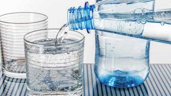 Aus einer Flasche wird Mineralwasser in ein Glas gegossen. © Fotolia Foto: v.poth
