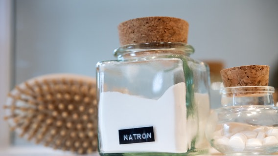 In einem Bad steht ein Glas mit Zahnputztablette, ein weiteres Glas mit Natron und eine Naturhaarbürste © picture-alliance/dpa Foto: Andrea Warnecke