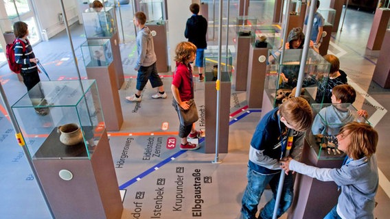 Kinder stehen vor Vitrinen in der Dauerausstellung des Archäologischen Museums in Harburg. © Archäologisches Museum Hamburg 