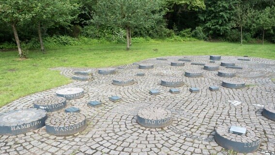 Eine gepflasterte Fläche bildet den Umriss von Schleswig-Holstein, weitere Steine symbolisieren die Städte des Landes. © NDR Foto: Anja Deuble