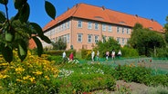 Blick auf das  Kloster Isenhagen und seinen Garten mit Besuchern. © imago images Foto: Wolf Winter
