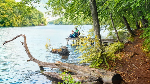 Zwei Wandernde sitzen auf einem Steg am Schmalen Luzin im Naturpark Feldberger Seenlandschaft. © Tourismusverband MV Foto: Andreas-Duerst.de