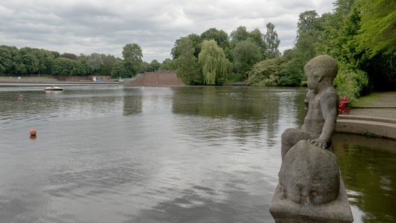 Eine Kinderfigur aus Stein blickt auf den See im Hamburger Stadtpark. © NDR Foto: Anja Deuble