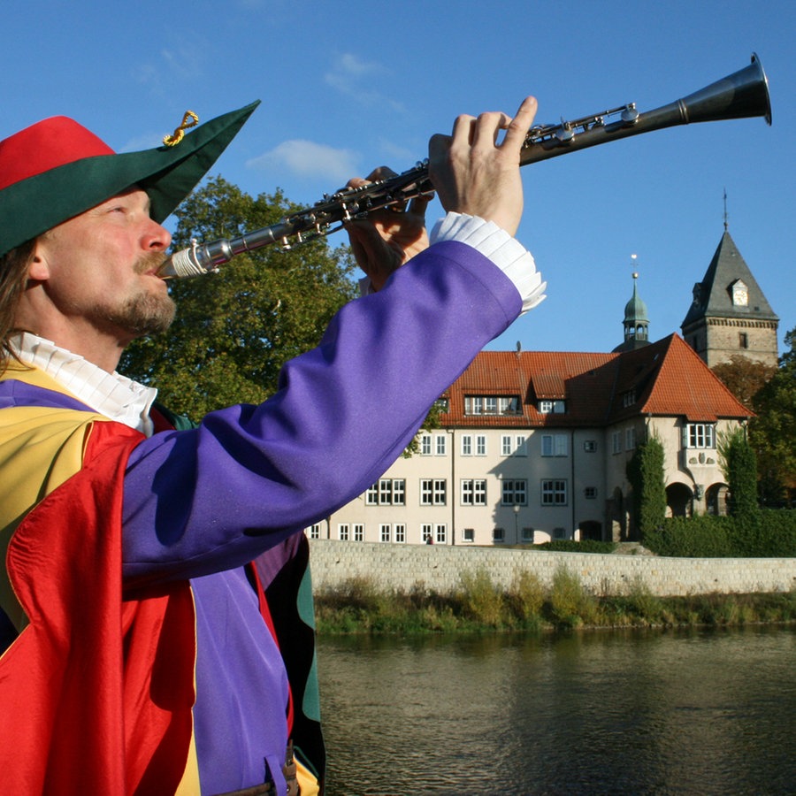 Der Rattenfänger von Hameln posiert mit seiner Flöte an der Weser. © Hameln Marketing und Tourismus GmbH 