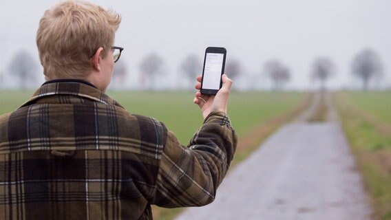 Mann hält ein Smartphone in die Luft © dpa Foto: Julian Stratenschulte