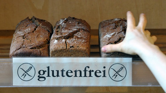 Eine Hand greift in einem Naturkostladen nach einem glutenfreien Brot. © Peter Endig / dpa Foto: Peter Endig