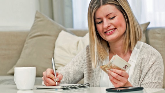 Eine Frau mit Notizblock beim Geldzählen. © Christian Klose 