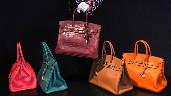 Fünf Bonhams Designer-Handtaschen nebeneinander, die mittlere wird hochgehoben. © Yui Mok/PA Foto: Yui Mok