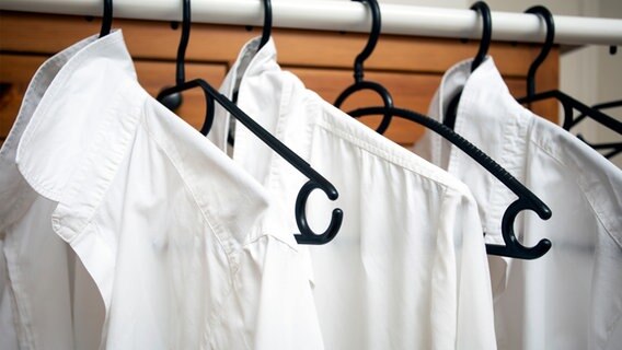 Weiße Hemden auf jedem zweiten Bügel an einer Kleiderstange. © photocase Foto: Annebel146