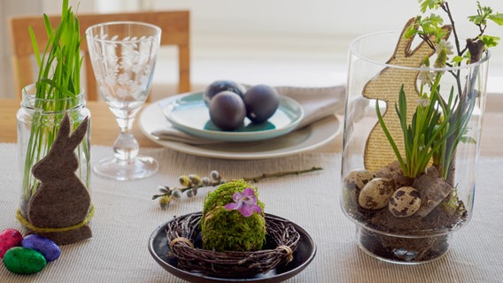 Ein Glas mit Katzengras, ein bemoostes Ei und ein Glas mit Oster-Dekoration stehen auf einem Tisch. © NDR Foto: Anja Deuble