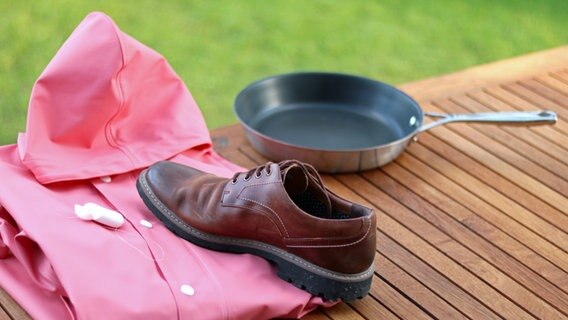 Regenjacke, Zahnseide, Gummistiefel, Bratpfanne und Einwegverpackungen für Fast Food auf einem Tisch © NDR Foto: Elke Janning