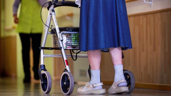 Eine alte Frau geht mit ihrem Rollator über einen Flur im Pflegeheim © Jens Büttner/dpa 