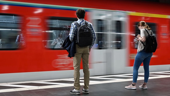 Ein Mann und eine Frau stehen auf einem Bahnsteig, auf dem eine S-Bahn einfährt. © dpa-Bildfunk Foto: Arne Dedert