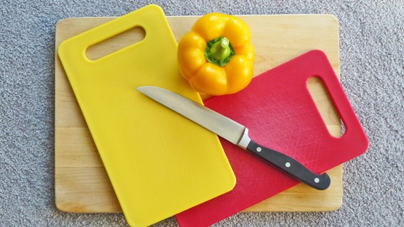 Schneidebretter aus Kunststoff und Holz sowie ein Messer und eine gelbe Paprika. © NDR Foto: Axel Franz