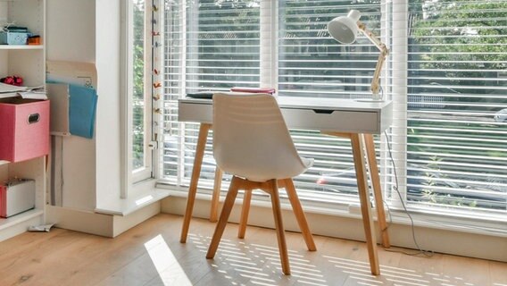 Ein kleiner weißer Schreibtisch mit Arbeitslampe und ein ein Stuhl vor einem Fenster © CasaMedia Charlotte Van Montpensierlaan Foto: CasaMedia Charlotte Van Montpensierlaan